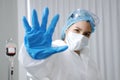 Asian Scientific experimenter Woman Wearing blue protective rubber gloves and showing stop hand sign for Covid-19 virus pathogens