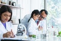 Asian scientist kid student and Indian teacher looking at plant in test bottle at biology class in school laboratory, do an Royalty Free Stock Photo