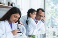 Asian scientist kid student and Indian teacher looking at plant in test bottle at biology class in school laboratory, do an Royalty Free Stock Photo