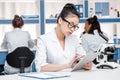 Asian scientist in lab coat with microscope and digital tablet working in chemical lab Royalty Free Stock Photo