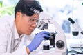 Asian scientist working in lab. Doctor making microbiology research. Laboratory tools: microscope, test tubes, equipment Royalty Free Stock Photo