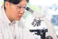 Asian scientist working in lab. Doctor making microbiology research. Laboratory tools: microscope, test tubes, equipment Royalty Free Stock Photo