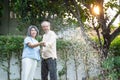 Asian Senior couple spending time outdoor gardening together at home. Attractive old grandparents use hose to watering Plants in Royalty Free Stock Photo