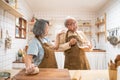 Asian senior couple standing in the kitchen at home, feeling happy and enjoy retirement life. Husband enjoy stirring eggs, wife