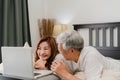 Asian senior couple using laptop at home. Asian Senior Chinese grandparents, husband and wife happy after wake up, watching movie Royalty Free Stock Photo