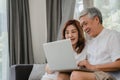 Asian senior couple using laptop at home. Asian Senior Chinese grandparents, surf the Internet to check social media while lying Royalty Free Stock Photo