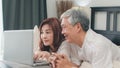 Asian senior couple using laptop at home. Asian Senior Chinese grandparents, husband and wife happy after wake up, watching movie Royalty Free Stock Photo