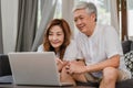 Asian senior couple using laptop at home. Asian Senior Chinese grandparents, surf the Internet to check social media while lying Royalty Free Stock Photo