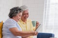 Asian senior couple using table compute and drink coffee sitting at sofa in living room at home.senior with technology lfiestyle. Royalty Free Stock Photo