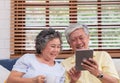 Asian senior couple using table compute and drink coffee sitting at sofa in living room at home.senior with technology lfiestyle.a Royalty Free Stock Photo