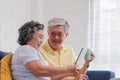 Asian senior couple using table compute and drink coffee sitting at sofa in living room at home.senior with technology lfiestyle.a Royalty Free Stock Photo