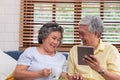 Asian senior couple using table compute and drink coffee sitting at sofa in living room at home.senior with technology lfiestyle.a Royalty Free Stock Photo