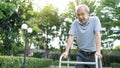 Asian Senior disabled man walking slowly with walker or cane at park. Older elderly mature handicapped patient male feeling