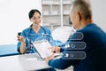 Asian Senior Doctor and patient discussing something while sitting at the table . Medicine and health care concept Royalty Free Stock Photo