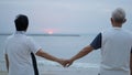 Asian senior elder couple holding hands looking sunset sea ocean together happy retirement life Royalty Free Stock Photo