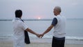 Asian senior elder couple holding hands looking sunset sea ocean together happy retirement life Royalty Free Stock Photo