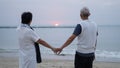 Asian senior elder couple holding hands looking sunset sea ocean together happy retirement life Royalty Free Stock Photo