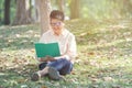 Asian senior elder woman read a book sit on green grass in public park with smile face - old age, retirement and people concept Royalty Free Stock Photo