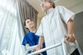 Asian Senior elderly disabled man patient walking slowly with walker at nursing home care. Caregiver therapist nurse support older Royalty Free Stock Photo