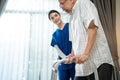 Asian Senior elderly disabled man patient walking slowly with walker at nursing home care. Caregiver therapist nurse support older Royalty Free Stock Photo