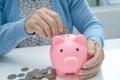 Asian senior or elderly old lady woman holding counting coin money in piggy bank. Poverty, saving problem  in retirement Royalty Free Stock Photo