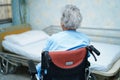Asian senior or elderly old lady woman patient sitting on wheelchair near bed in nursing hospital ward Royalty Free Stock Photo