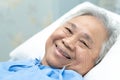 Asian senior or elderly old lady woman patient smile bright face with strong health while lying on bed in nursing hospital Royalty Free Stock Photo