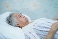 Asian senior or elderly old lady woman patient smile bright face with strong health while lying on bed in nursing hospital ward Royalty Free Stock Photo