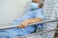 Asian senior or elderly old woman patient wearing mask for protect coronavirus lie down handle the rail bed with hope on a bed in Royalty Free Stock Photo