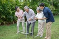 asian senior father trying walk with walker and adult son daughter wife support in gaden at home. old man disabled walking and Royalty Free Stock Photo