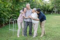 asian senior father trying walk with walker and adult son daughter wife support in gaden at home. old man disabled walking and Royalty Free Stock Photo