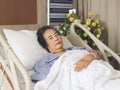 Asian senior female patient  lying down  in hospital bed, looking at camera. Elderly health concept Royalty Free Stock Photo