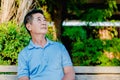 Asian senior gentleman thinking while looking up and sitting on a wooden bench with relaxing in a park  on a sunny day Royalty Free Stock Photo