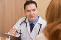 Asian Senior male Doctor discussing with female patient. Royalty Free Stock Photo