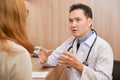 Asian Senior male Doctor discussing with female patient. Royalty Free Stock Photo