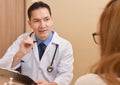 Asian Senior male Doctor talking to female patient. Royalty Free Stock Photo