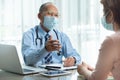 Asian Senior Male Doctor wearing protective face mask talking with female patient Royalty Free Stock Photo