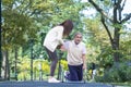 Asian senior man is accidentally fall over in the park due to the slippery road while his niece is lifting him up in injury for Royalty Free Stock Photo