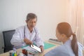 Asian Senior man doctor talking with female patient in doctors office. Royalty Free Stock Photo