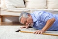 Asian senior man falling down on carpet and lying on the floor in living room at home.