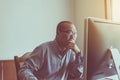 Asian senior man serious working and using computer at home in the morning