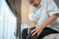 Asian Senior man sit on sofa, suffer from injured leg at nursing home. Painful Mature Older Elderly retired male patient suffering