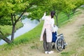 Asian senior man sitting on a wheelchair with caregiver pointing Royalty Free Stock Photo