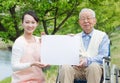 Asian senior man sitting on a wheelchair with caregiver and white board Royalty Free Stock Photo