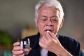 Asian senior man taking pills at home Royalty Free Stock Photo