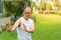 Asian senior man wear white shirt stand and practice tai chi in the park and copy apace