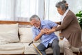 Asian senior man with pain on heart on sofa in living room and take care by his wife.