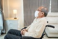 Asian Senior old male wear face mask, sit alone on wheelchair in house. Unhappy elderly disabled man feeling lonely and worry from Royalty Free Stock Photo