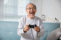 Asian senior old man enjoying holding joystick playing video game at home Royalty Free Stock Photo