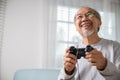 Asian senior old man enjoying holding joystick playing video game at home Royalty Free Stock Photo